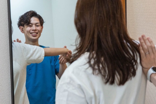 鏡の前で、施術者が姿勢や可動域を丁寧に確認している様子
